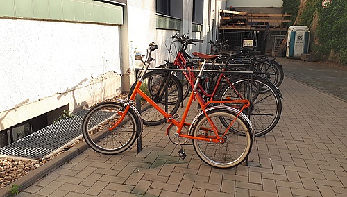 Oranges Klappfahrrad am Fahrradständer
