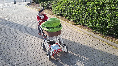 Mika mit Puppenwagen auf dem Weg zum Bäcker