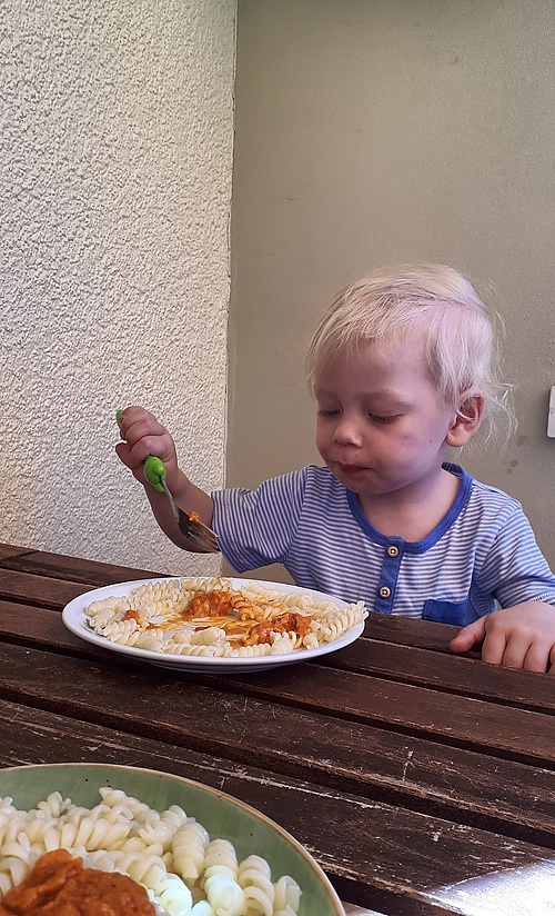 Mika beim Nudeln essen auf dem Balkon